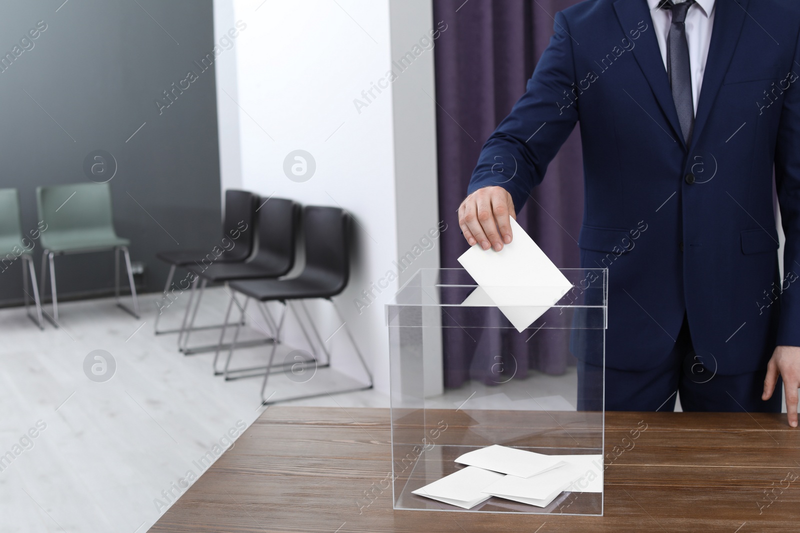 Photo of Man putting his vote into ballot box at polling station, closeup. Space for text