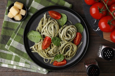 Photo of Tasty pasta with spinach, sauce and tomatoes served on wooden table, flat lay