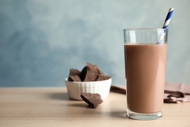 Photo of Glass of tasty chocolate milk on wooden table, space for text. Dairy drink