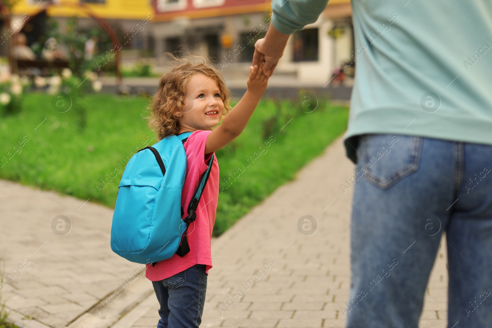 Photo of Woman and her little daughter on their way to kindergarten outdoors, closeup