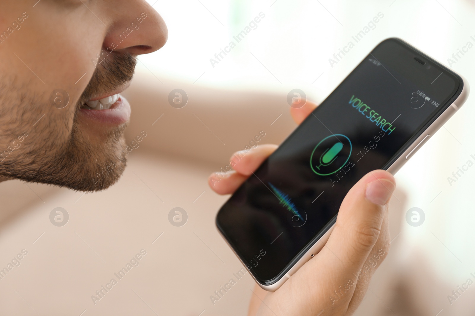 Photo of Young man using voice search on smartphone indoors, closeup