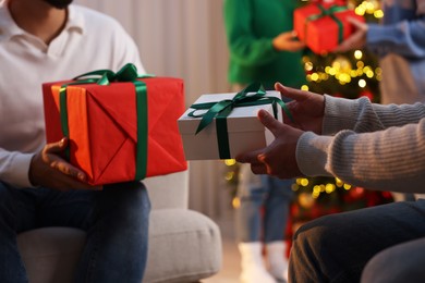 Photo of Christmas celebration. Happy friends exchanging gifts at home, closeup