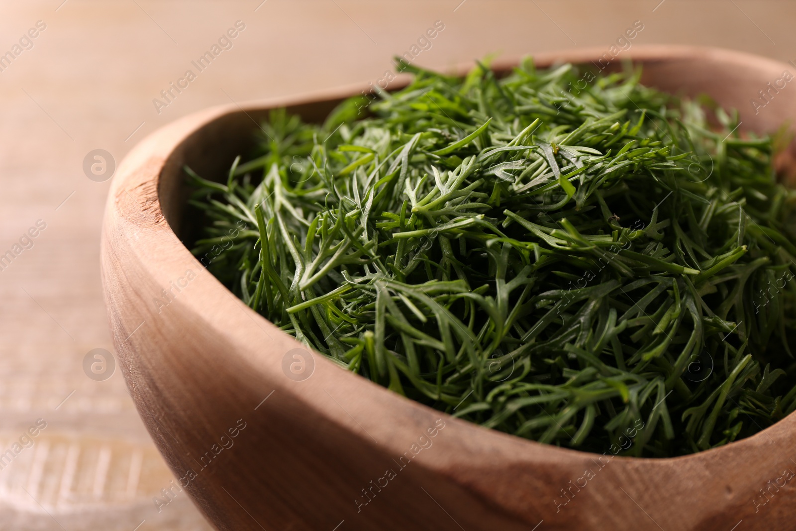 Photo of Fresh cut dill in wooden bowl on table, closeup