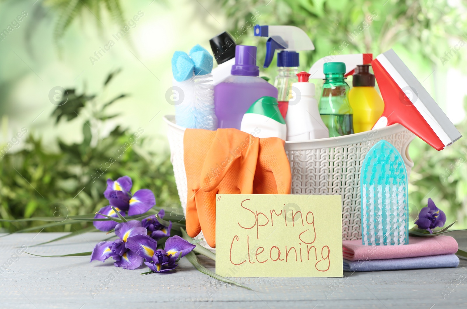 Photo of Spring flowers and cleaning supplies on light wooden table