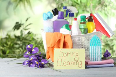 Photo of Spring flowers and cleaning supplies on light wooden table