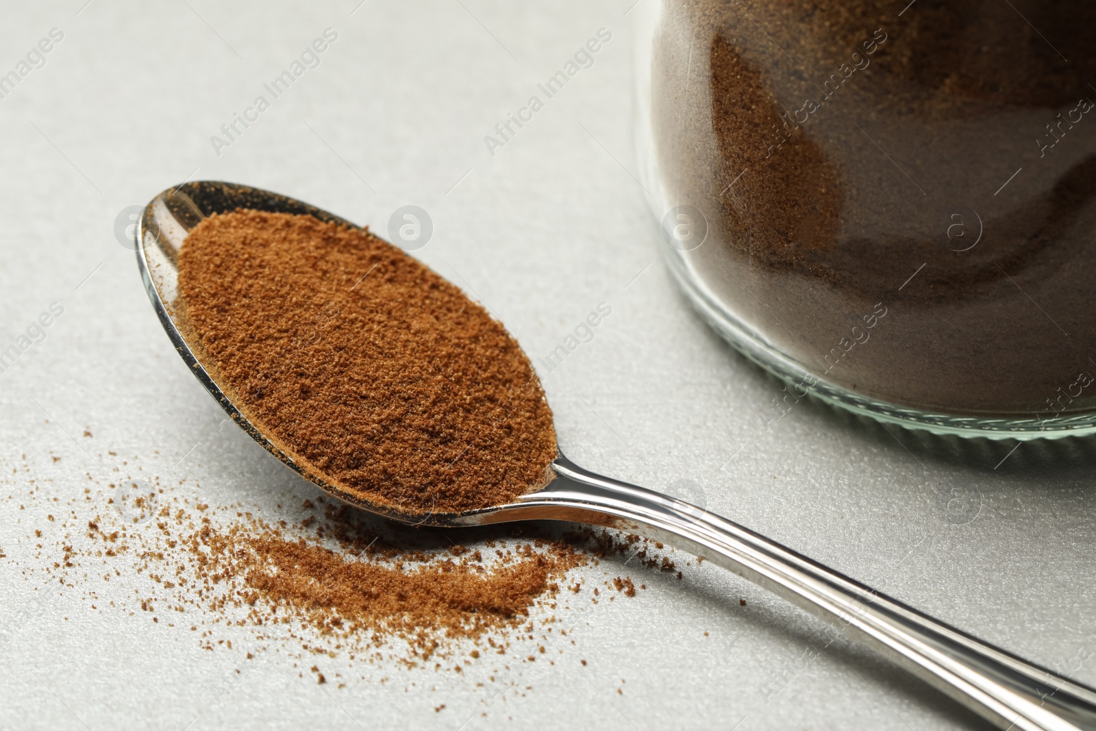 Photo of Spoon of chicory powder on light grey table, closeup