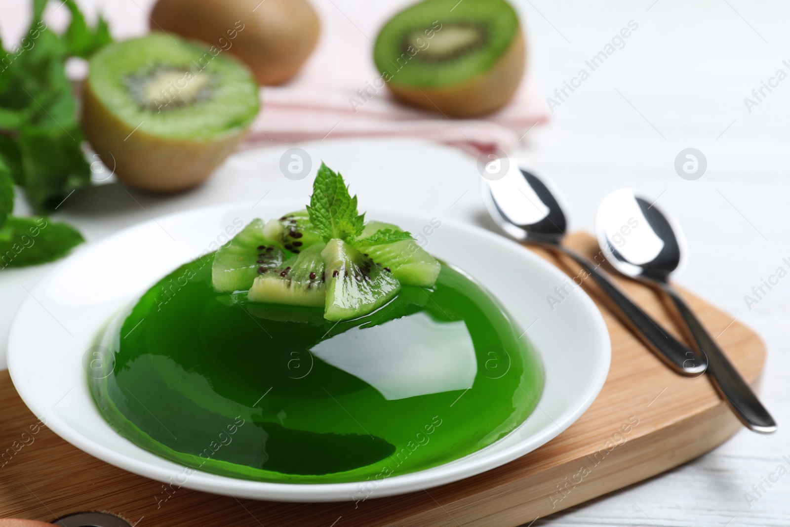 Photo of Delicious green jelly with kiwi slices on white wooden table