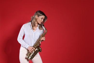 Photo of Beautiful young woman playing saxophone on red background. Space for text