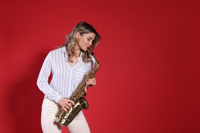 Beautiful young woman playing saxophone on red background. Space for text