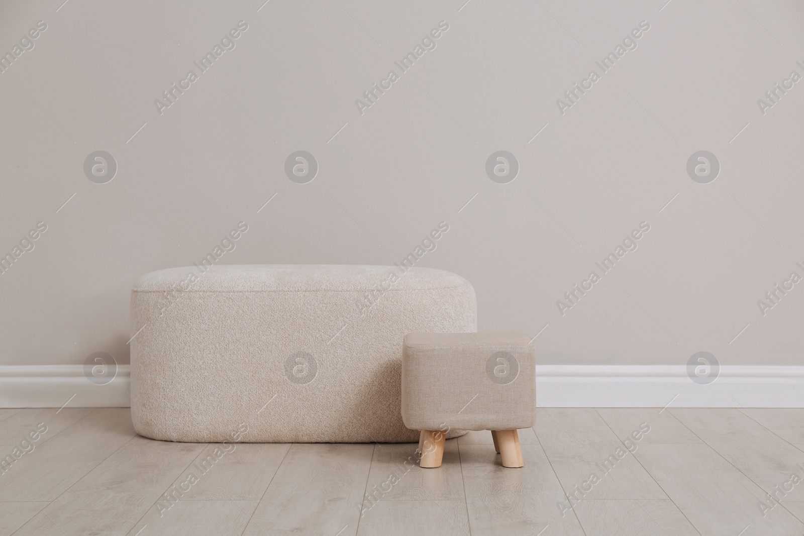 Photo of Stylish poufs near beige wall indoors. Space for text