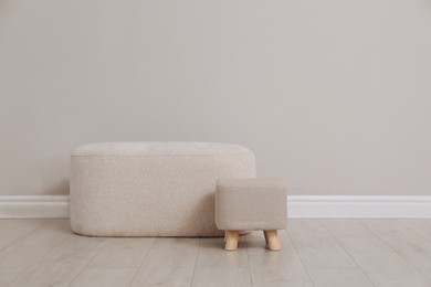 Photo of Stylish poufs near beige wall indoors. Space for text