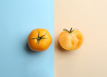 Photo of Whole and cut yellow tomatoes on color background, flat lay