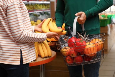 Photo of Couple with shopping basket in supermarket, closeup