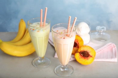 Delicious milk shakes and ingredients on table against color background