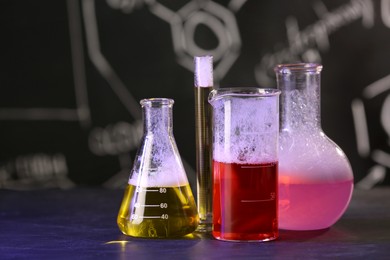 Photo of Laboratory glassware with colorful liquids on black table, space for text. Chemical reaction