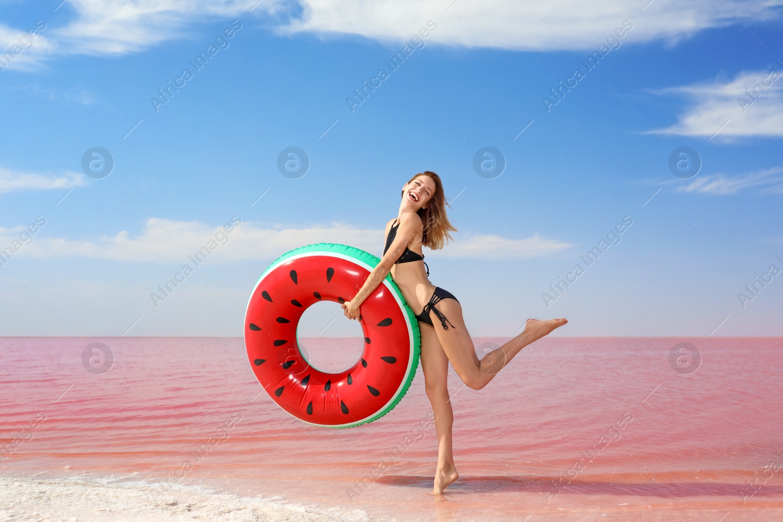 Photo of Beautiful woman with inflatable ring posing near pink lake on sunny day