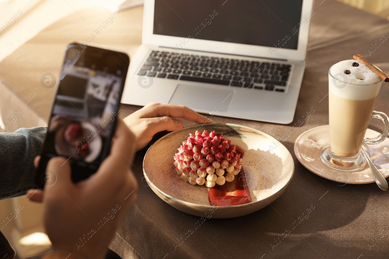 Photo of Young blogger taking picture of dessert at table in cafe, closeup