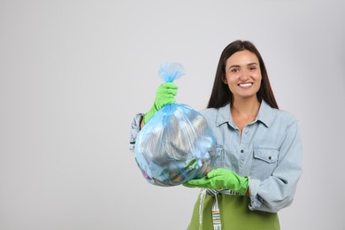 Photo of Woman holding full garbage bag on light background. Space for text