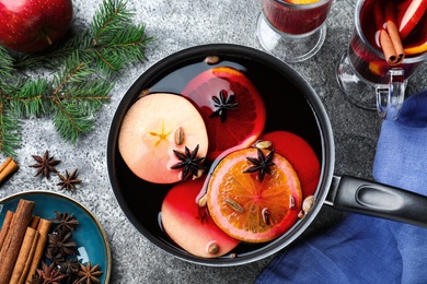 Photo of Delicious mulled wine and ingredients on grey table, flat lay