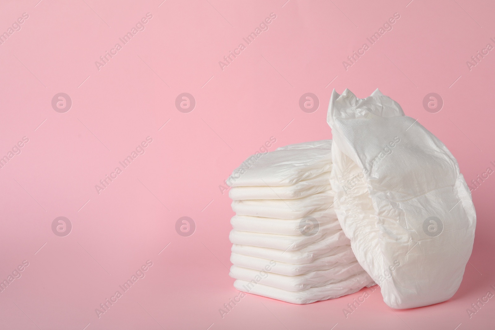 Photo of Stack of diapers on pink background. Space for text