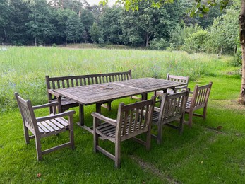 Wooden table with bench and chairs in garden. Landscape design