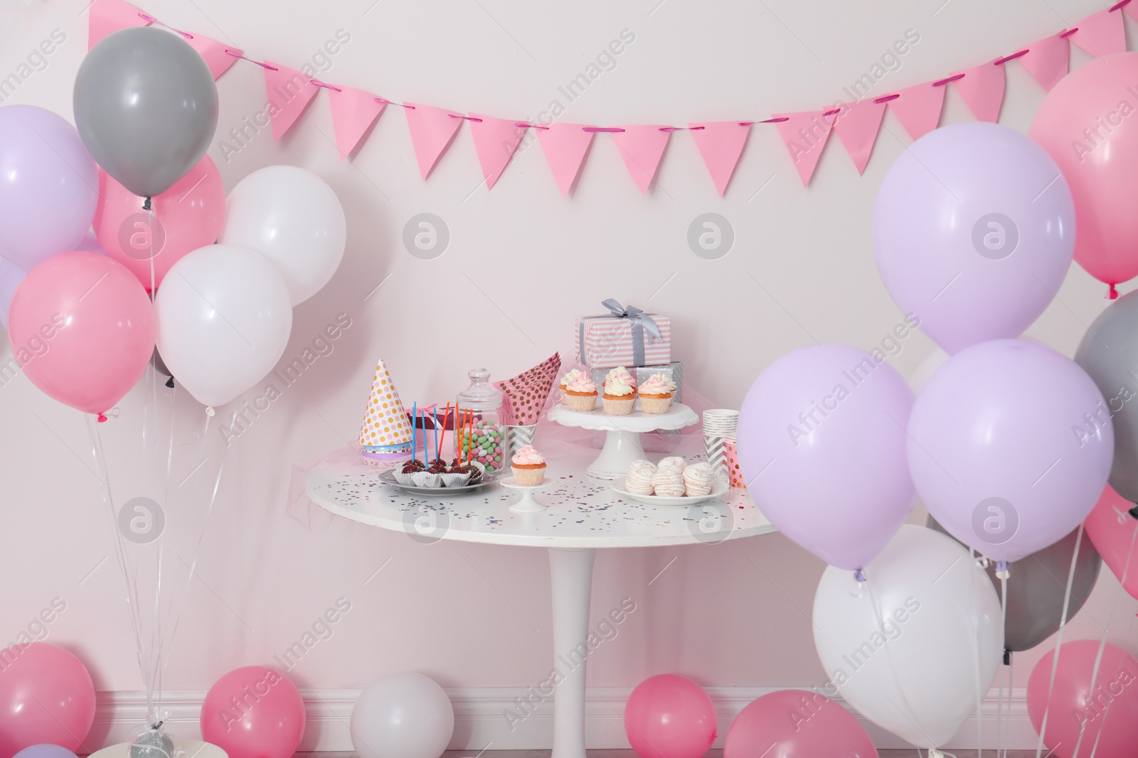 Photo of Party treats and items on table in room decorated with balloons