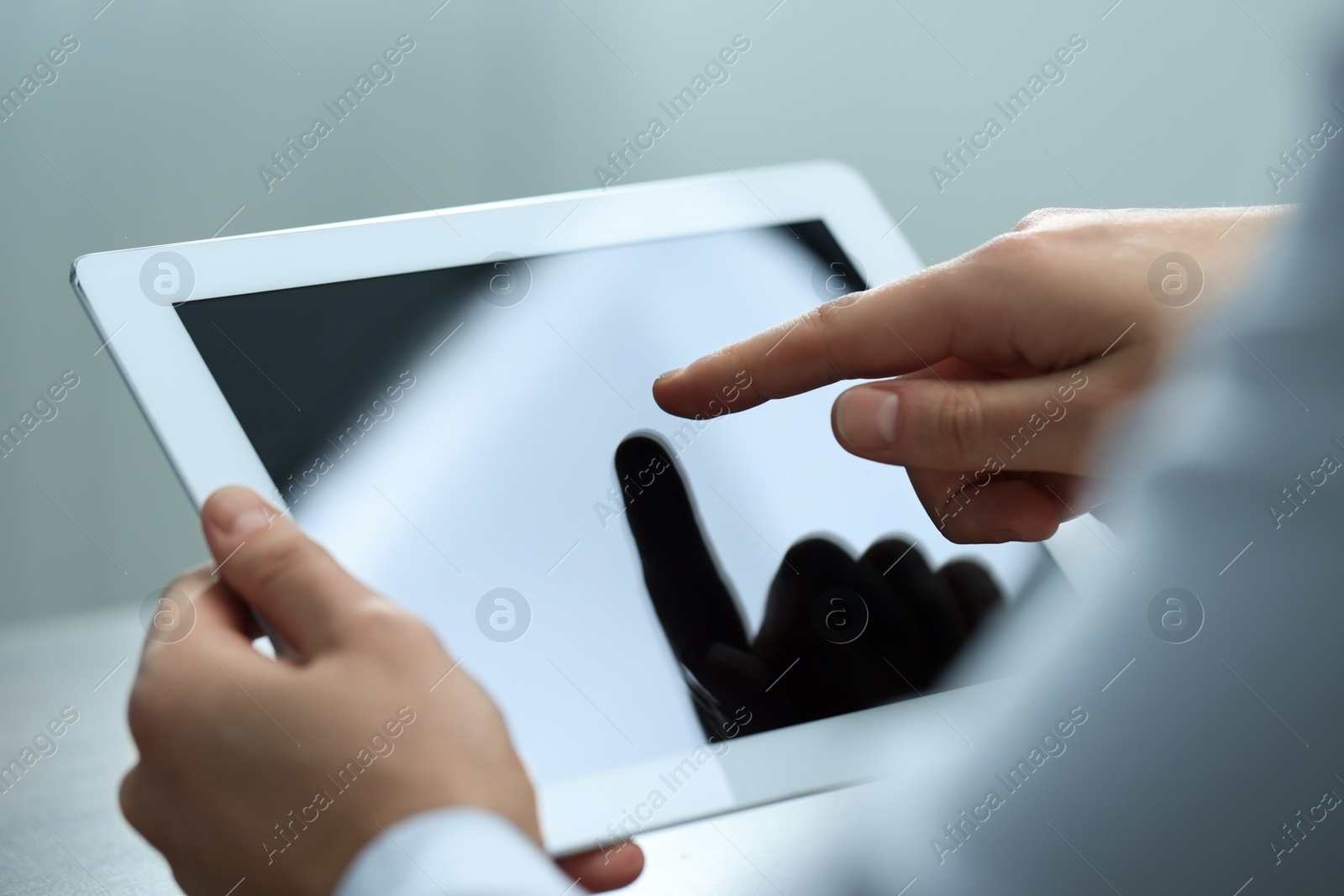 Photo of Man using tablet on light grey background, closeup