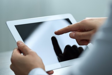 Man using tablet on light grey background, closeup