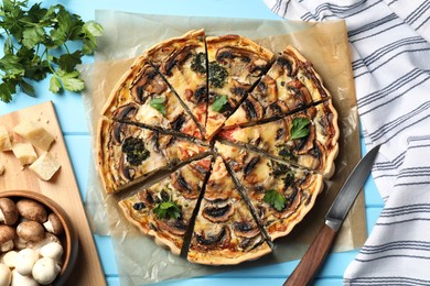 Photo of Delicious quiche with mushrooms and ingredients on light blue wooden table, flat lay