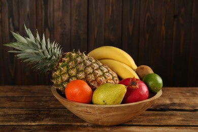 Photo of Fresh ripe fruits in bowl on wooden table