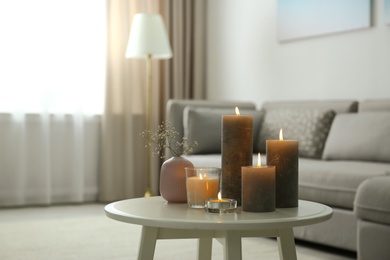 Photo of Burning decorative candles on table in room