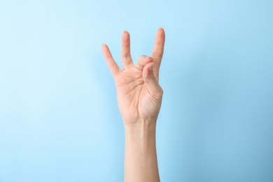 Woman showing number eight on color background, closeup. Sign language