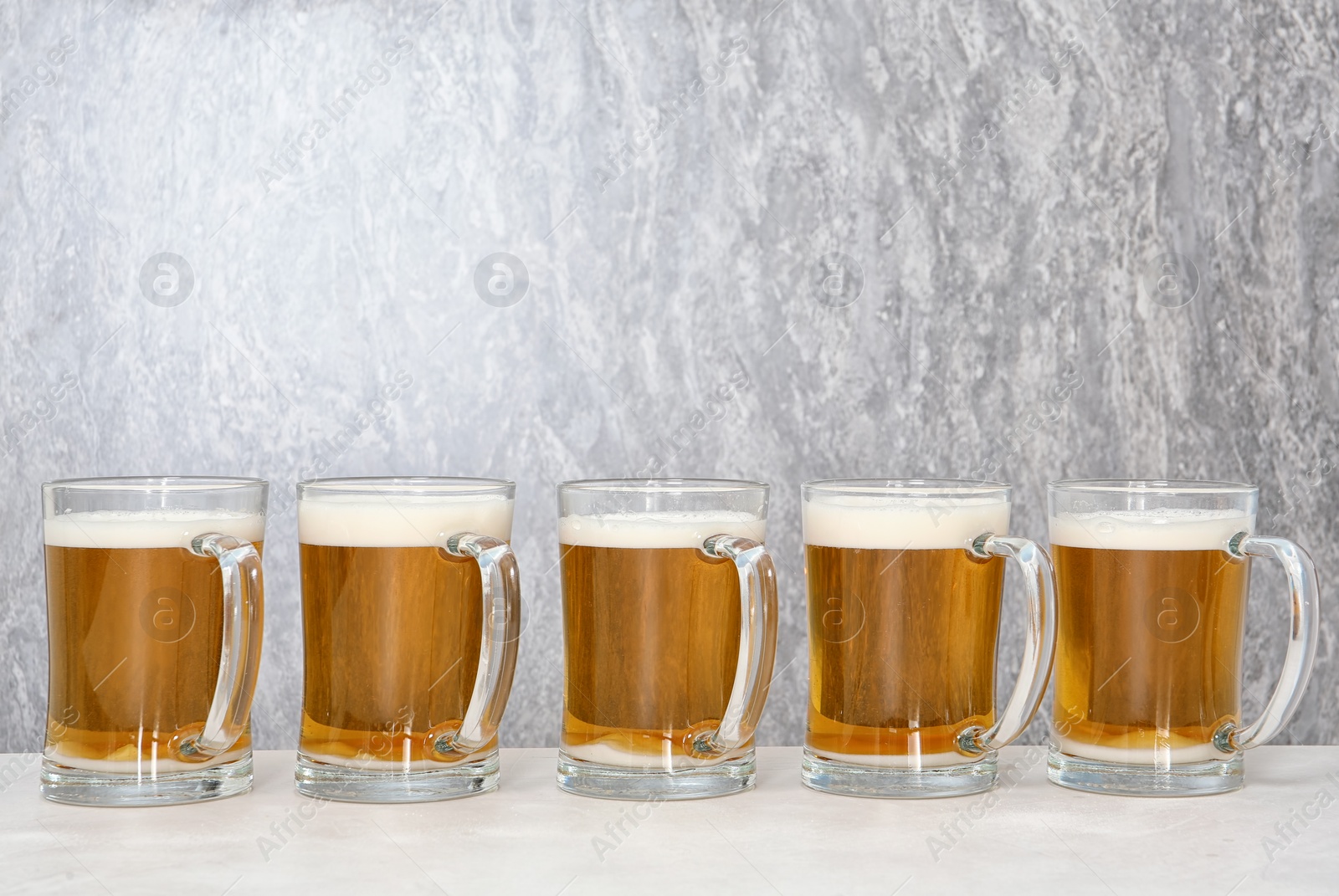 Photo of Row of glass mugs with beer on table