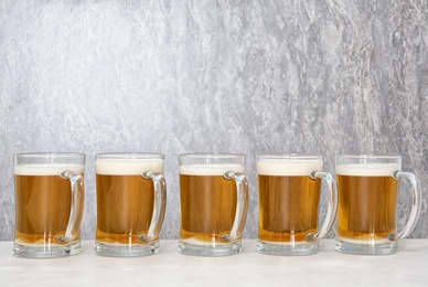 Photo of Row of glass mugs with beer on table