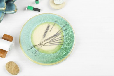 Flat lay composition with acupuncture needles on white wooden table. Space for text