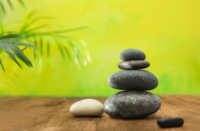 Photo of Table with stack of stones and blurred green leaves on background, space for text. Zen concept