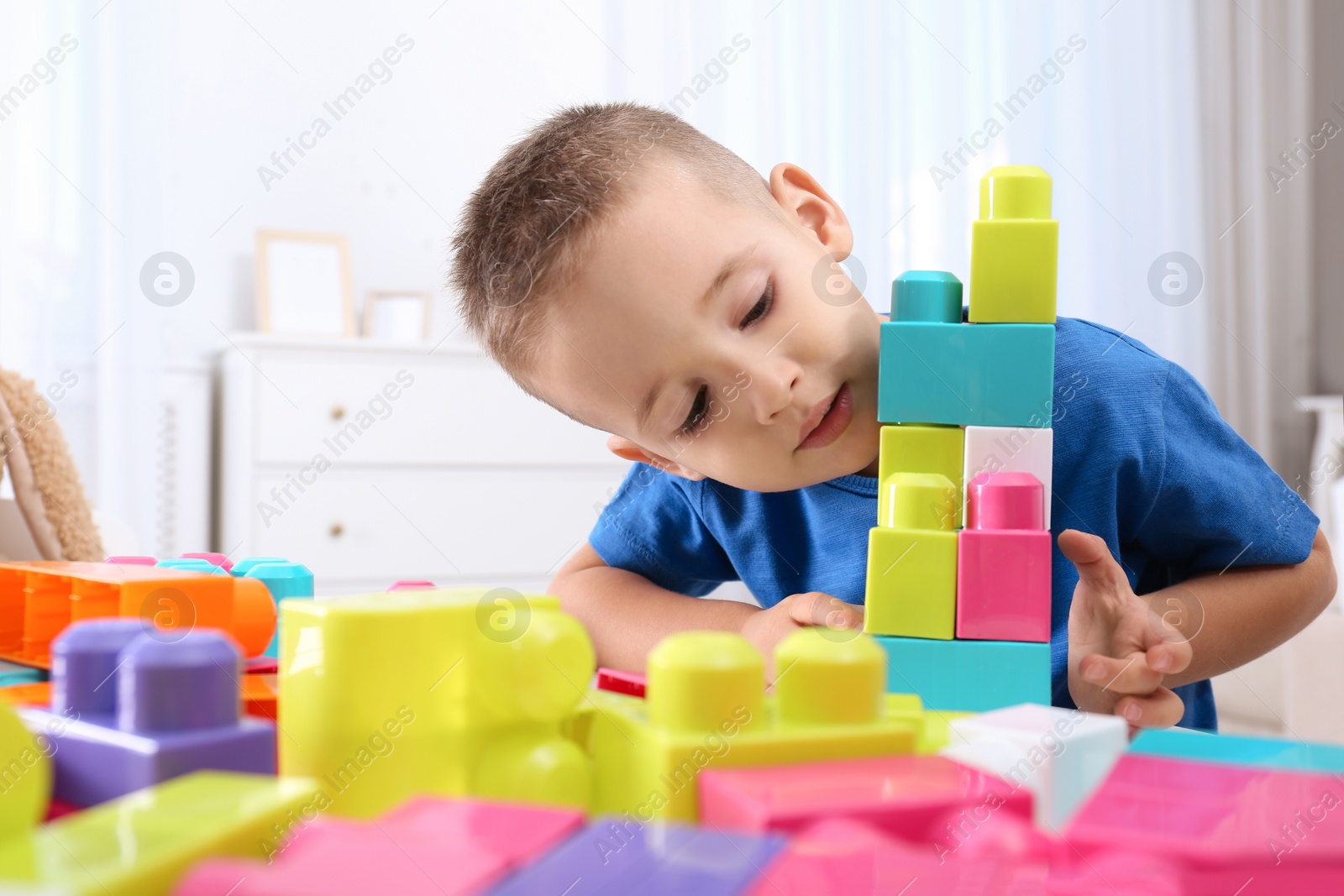 Photo of Cute little boy playing with colorful building blocks at table in room