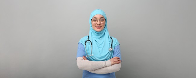 Muslim woman in hijab, medical uniform with stethoscope on light grey background. Banner design