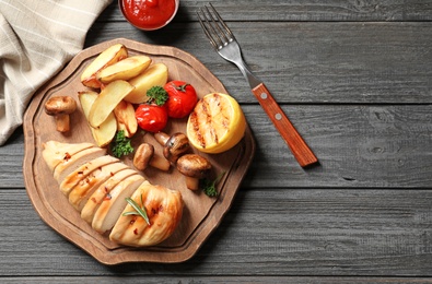 Fried chicken breast served with sauce and garnish on wooden background, top view. Space for text