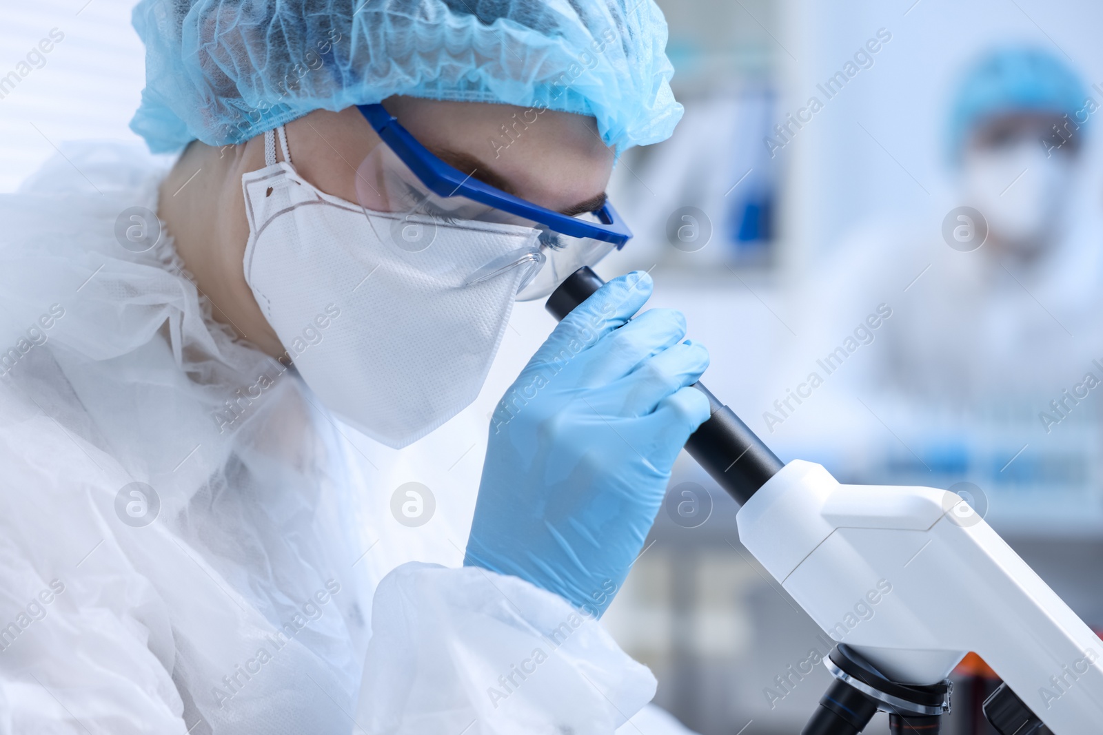 Photo of Scientist working with samples and microscope in laboratory, closeup