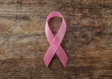 Pink ribbon on wooden background, top view. Breast cancer awareness concept