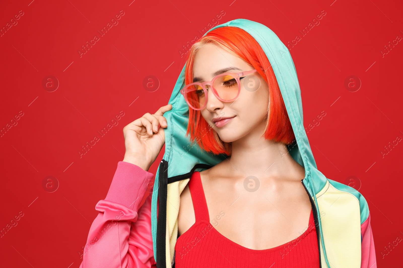 Photo of Beautiful young woman with bright dyed hair on red background