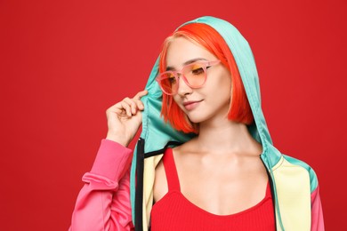 Beautiful young woman with bright dyed hair on red background