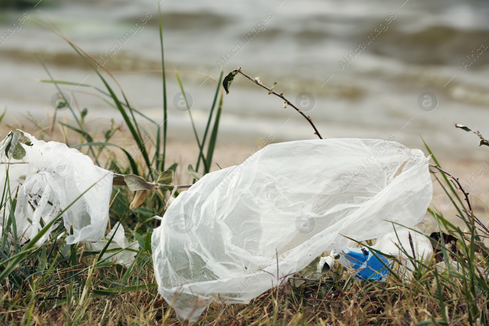 Photo of Plastic garbage scattered on grass near river