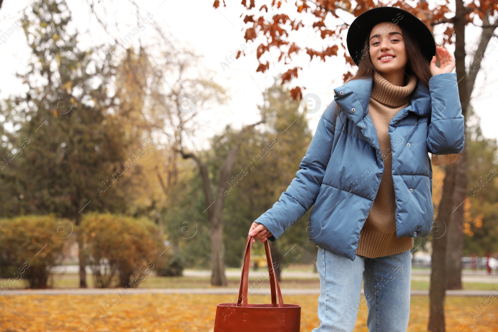 Photo of Young woman wearing stylish clothes in autumn park, space for text