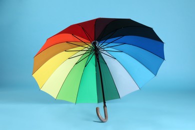 Stylish open bright umbrella on light blue background