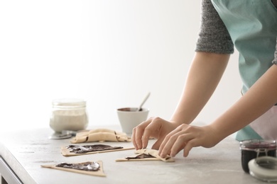 Photo of Woman preparing tasty croissants with chocolate paste at table in kitchen
