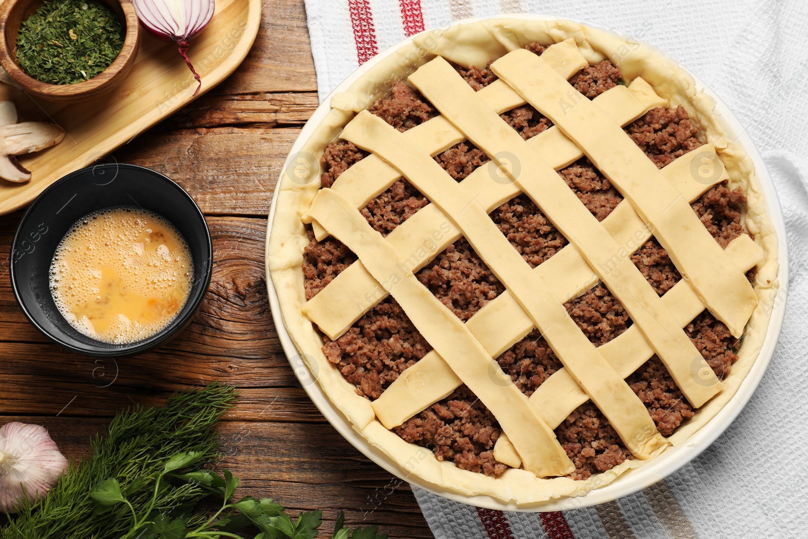 Photo of Raw meat pie and ingredients on wooden table, flat lay