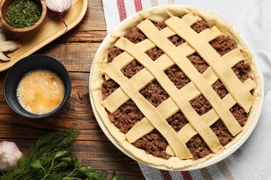 Raw meat pie and ingredients on wooden table, flat lay