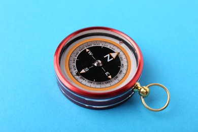 Photo of Compass on light blue background. Navigation equipment